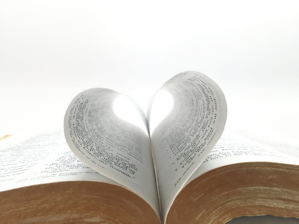 Open Bible with pages forming a heart shape, symbolizing God's love through Scripture.