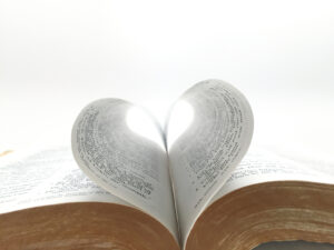 Open Bible with pages forming a heart shape, symbolizing God's love through Scripture.