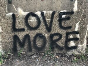 Graffiti on a concrete wall that reads “LOVE MORE,” symbolizing the radical call to love our enemies as Jesus commands in Matthew 5:44.