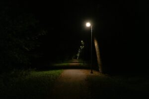 A dark path lit by streetlights symbolizing spiritual battle and the light of God’s Word overcoming darkness