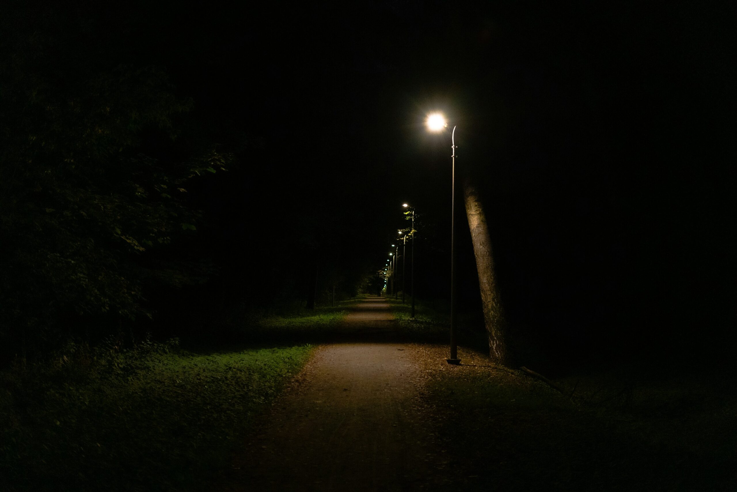 A dark path lit by streetlights symbolizing spiritual battle and the light of God’s Word overcoming darkness